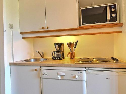 une petite cuisine avec un évier et un micro-ondes dans l'établissement Studio-cabine équipé au pied des pistes à Belle Plagne - FR-1-455-221, à La Plagne Tarentaise