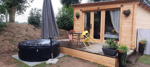 a wooden deck with a table and an umbrella at Chalet Studio 5kms Etretat in Villainville