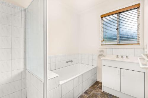 a white bathroom with a bath tub and a window at Views on Bayview in Cowes