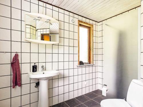 uma casa de banho em azulejos brancos com um lavatório e um espelho. em Holiday home Øster Assels VII em Øster Assels