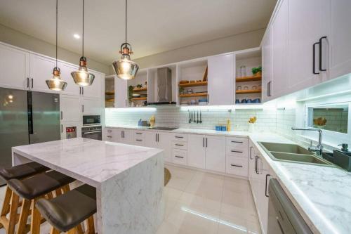 チャングーにあるVilla Ammanya - Modern 3-bedroom luxury villa in amazing location!のキッチン(白いキャビネット、大理石のカウンタートップ付)