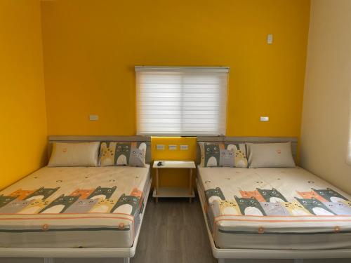 Duas camas num quarto com paredes amarelas em Wen Wen Sub BnB em Magong