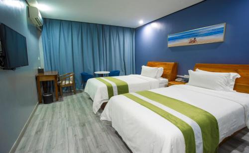 a hotel room with two beds and a flat screen tv at Junlan Hotel in Sihanoukville