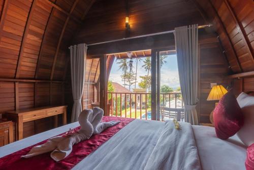 1 dormitorio con 1 cama y vistas a un balcón en Kukuh Penida Village en Nusa Penida