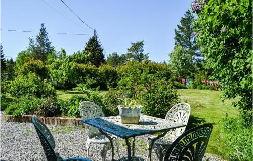 a table and chairs in a garden with a vase on it at Awesome Home In Hallstavik With Wifi in Hallstavik