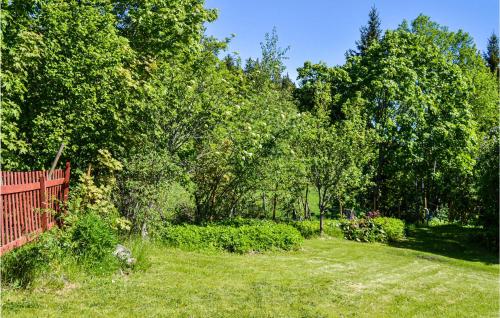 a yard with a red fence and trees at Awesome Home In Hallstavik With Wifi in Hallstavik