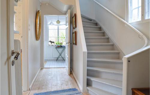 a hallway with white stairs with a blue rug at Awesome Home In Hallstavik With Wifi in Hallstavik