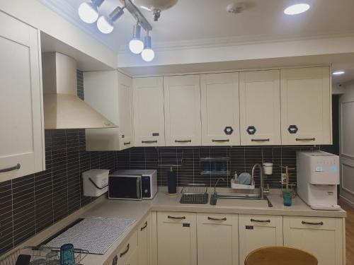 a kitchen with white cabinets and a sink at Elephant Hostel Nampo in Busan