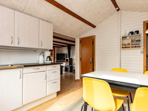 a kitchen with white cabinets and yellow chairs at 6 person holiday home in Sp ttrup in Lihme
