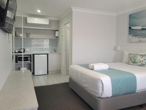 a bedroom with a large bed and a kitchen at Araluen Motor Lodge in Batemans Bay