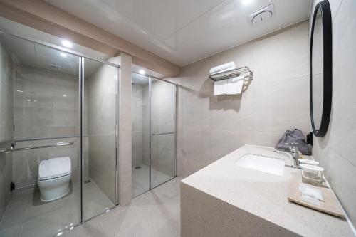 a bathroom with a shower and a toilet and a sink at Geoje Mongdol Beach H Avenue Hotel in Geoje 