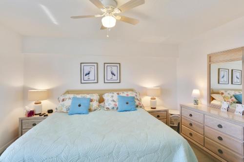 een slaapkamer met een bed met blauwe kussens en een plafondventilator bij Amadeus 10 in St Pete Beach