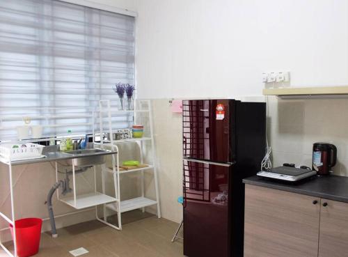 cocina con fregadero y nevera negra en The_Mozy Homestay, en Tanjong Sepat