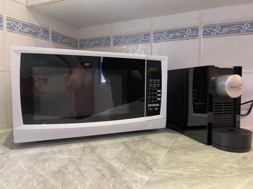 a microwave oven with a person taking a picture at Cozy 3 bedroom and office space in center of Kallangur in Kallangur