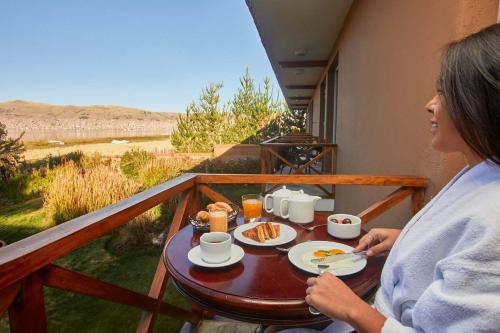 eine Frau auf einem Balkon mit einem Tisch mit Essen in der Unterkunft Casa Andina Premium Puno in Puno