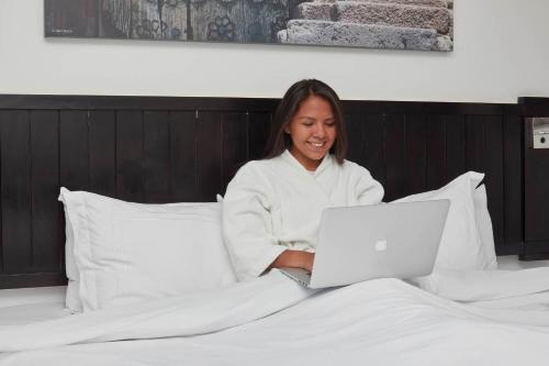 a woman sitting on a bed with a laptop at Casa Andina Premium Puno in Puno
