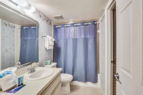 a bathroom with a toilet sink and a blue shower curtain at Emerald Isle 602 in St. Pete Beach