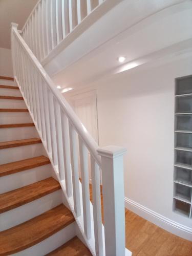 a staircase in a house with white walls and wood floors at Gwandalan - 1 Bed Apartment, Within Tenby Town Walls in Tenby
