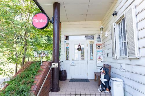 a dog sits on the porch of a house at Tabist Kiyosato Grandeur Yatsugatake in Hokuto