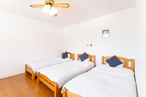three beds in a room with a ceiling fan at Tabist Kiyosato Grandeur Yatsugatake in Hokuto