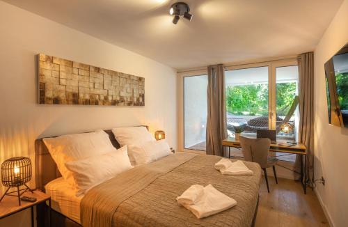 a bedroom with a bed and a desk and a window at SweetHome - Luxus pur - große Küche, 2 Bäder, 2 Terrassen in Ottobrunn