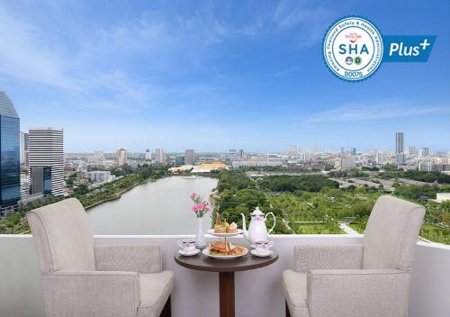 een balkon met 2 stoelen en een tafel met uitzicht op een rivier bij Centre Point Sukhumvit 10 in Bangkok