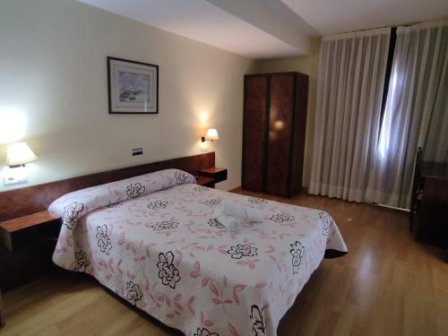 1 dormitorio con 1 cama con colcha rosa en HOTEL EL MOLINO DE PANCORBO, en Pancorbo
