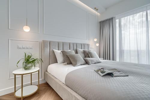 een witte slaapkamer met een groot bed en een raam bij Apartament Ariela LUX 17th fl HANZA in Szczecin