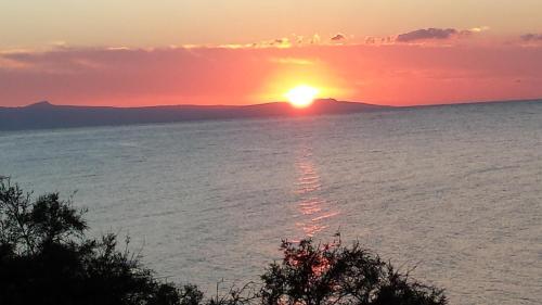 a sunset over the water with the sun in the sky at Sun Camero Apartments in Pomos
