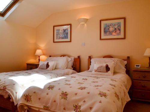 two twin beds in a bedroom with two pictures on the wall at Cider Press Cottage in Blakeney