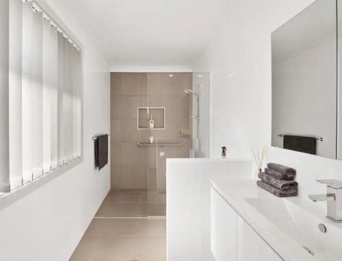 a white bathroom with a shower and a sink at Guest House On Guy in Forster