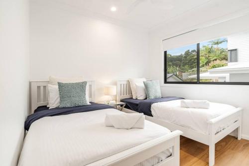 two beds in a white room with a window at Coast in Lennox Head