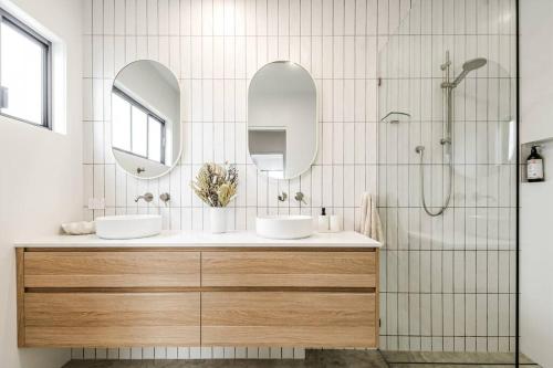 a bathroom with two sinks and two mirrors at Coast in Lennox Head