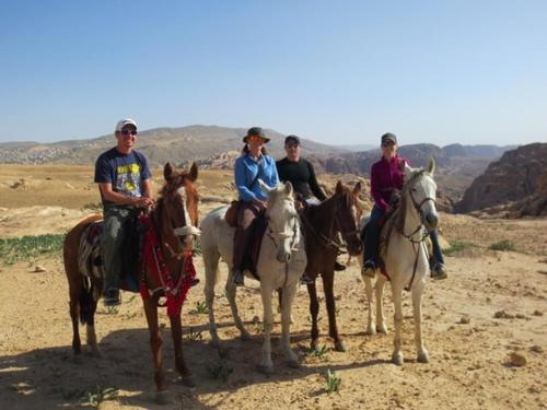 a group of people riding horses in the desert at Happy Bedouin House Petra in Al Ḩayy