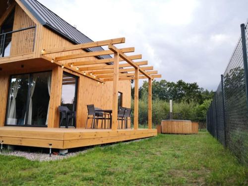 a house with a deck with a table and chairs at Sielanka Szkotowo domek z jacuzzi in Szkotowo