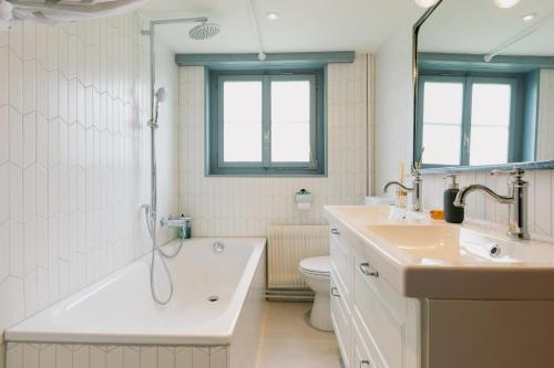 a bathroom with a tub and a sink and a toilet at The Farmhouse in Sedrun