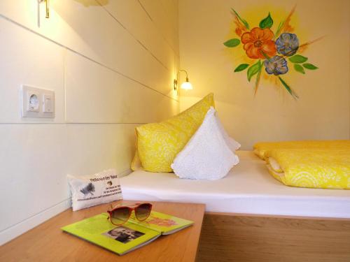 a room with a bed with a book and sunglasses on a table at Haus Hoher Sattel in Leutasch