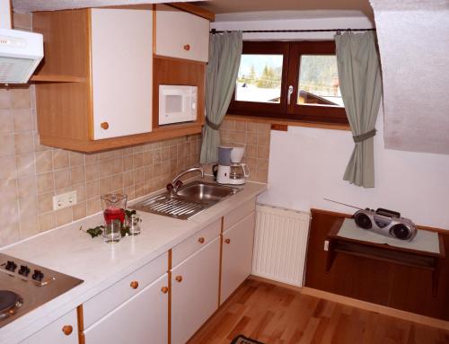 a kitchen with white cabinets and a sink and a window at Haus Hoher Sattel in Leutasch