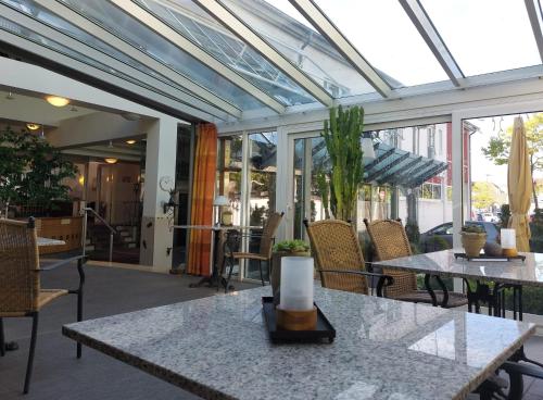 a conservatory with tables and chairs and windows at Hotel Goldener Stern in Sankt Ingbert