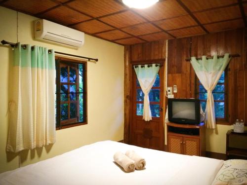 a bedroom with a bed and a tv and windows at Sangsawang Resort in Mae Hong Son