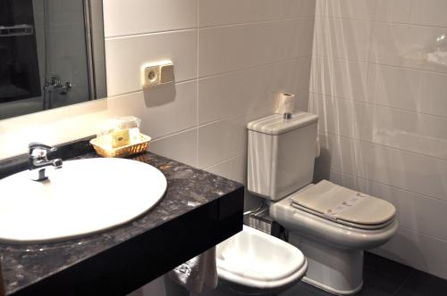 a bathroom with a white toilet and a sink at Hotel Crunia I A Coruña in A Coruña