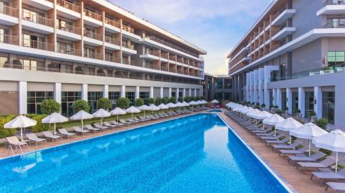 a swimming pool with chairs and umbrellas next to a building at Acanthus Cennet Barut Collection - Ultra All Inclusive in Side