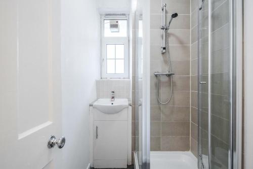 uma casa de banho branca com um chuveiro e um lavatório. em APlaceToStay Central London Apartment, Zone 1 KIN em Londres