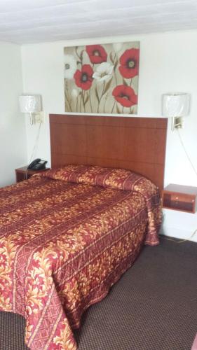 a hotel room with a bed and a painting on the wall at Royal Inn Motel in Watertown