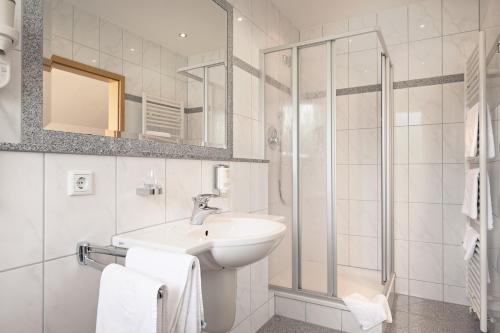 La salle de bains blanche est pourvue d'un lavabo et d'une douche. dans l'établissement Hotel Heuboden, à Umkirch