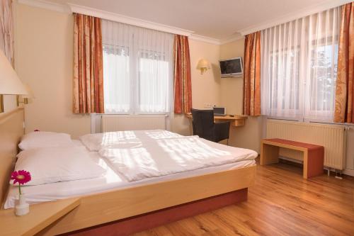 a bedroom with a bed and a desk and windows at Hotel Heuboden in Umkirch