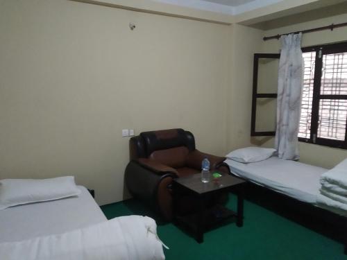 una camera con due letti, una sedia e un tavolo di Diya's Guest House a Bandipur