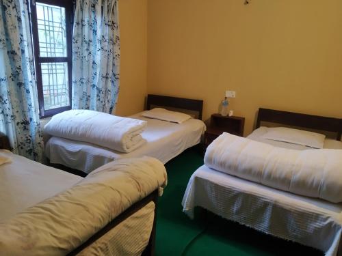 a room with three beds and a window at Diya's Guest House in Bandipur