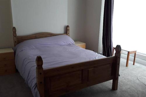 Cama de madera en un dormitorio con ventana en Porthcawl House Near Beach With Extensive Parking, en Porthcawl