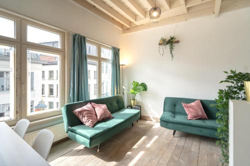 a living room with two green couches and windows at Tempel Cathedral Lodge in the Heart of Antwerp in Antwerp